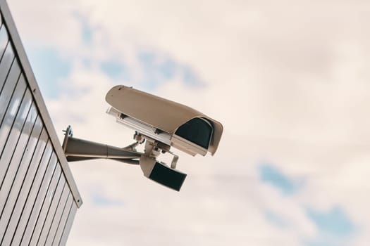 A modern security camera is installed on a building, continuously observing and monitoring the surrounding area