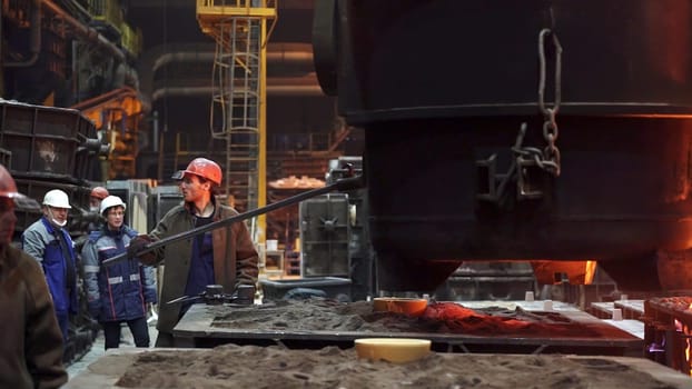 A detailed view of professionals in a metal casting facility, emphasizing teamwork and industrial processes. Stock Clip