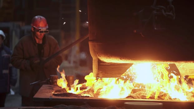A skilled worker expertly manages the intricate process of pouring molten metal in a hightemperature foundry. Stock Clip