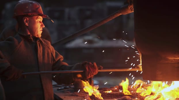 Workers expertly manage molten metal in a furnacelit factory, demonstrating their skill and precision. Stock Clip