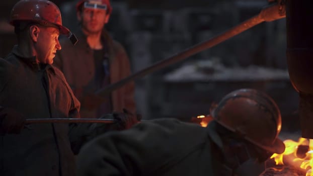 The metalworking scene is vibrant with workers pouring molten material, highlighting their skills and craftsmanship. Stock Clip