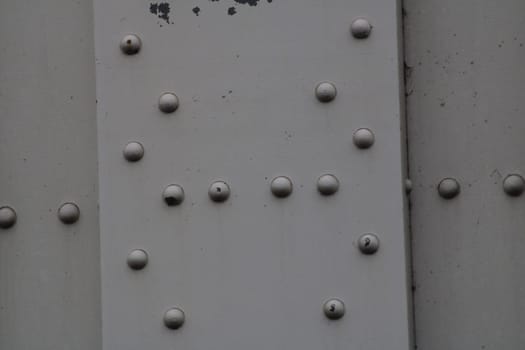 The metal surface features a series of rivets in varying sizes and conditions, capturing the essence of industrial design. This texture highlights wear and age.
