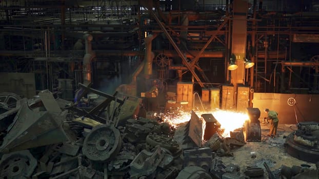 A captivating view of a sprawling industrial setting showcasing the process of melting metal amidst machinery debris. Stock Clip
