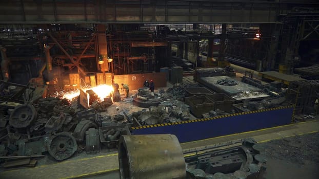 This is a captivating inside view of a bustling foundry, vividly showcasing the molten metal as its being poured. Stock Clip