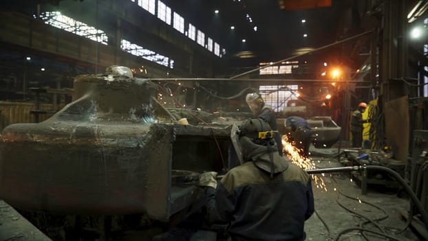 Workers skillfully operate heavy machinery in a dimly lit foundry during the intricate metal casting process. Stock Clip
