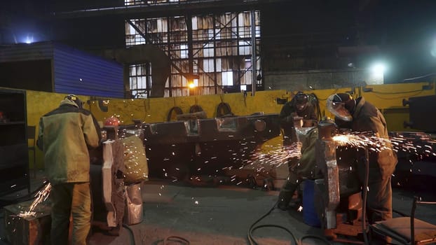 Under bright and vivid lights, men are diligently welding metal structures at a bustling construction site. Stock Clip