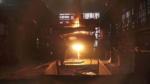 An industrial worker processing metal in a dimly lit foundry, creating a dramatic and intense scene. Stock Clip
