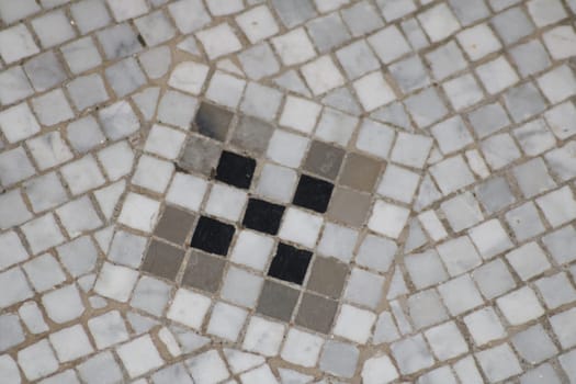 A distinct mosaic tile arrangement showcases a geometric design composed of gray and black tiles. This decorative flooring reflects traditional craftsmanship, typical in historic locations.