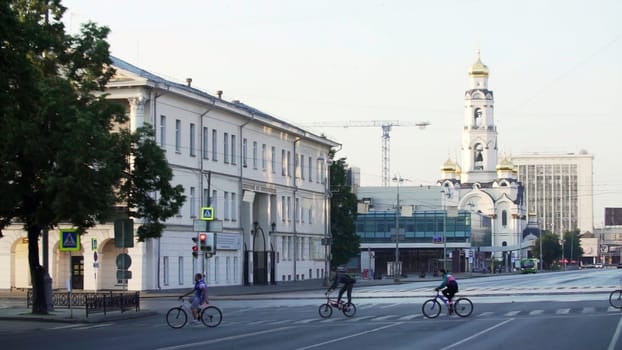 A tranquil urban scene showcasing cyclists gracefully crossing a calm street beside contemporary architecture. Stock Clip