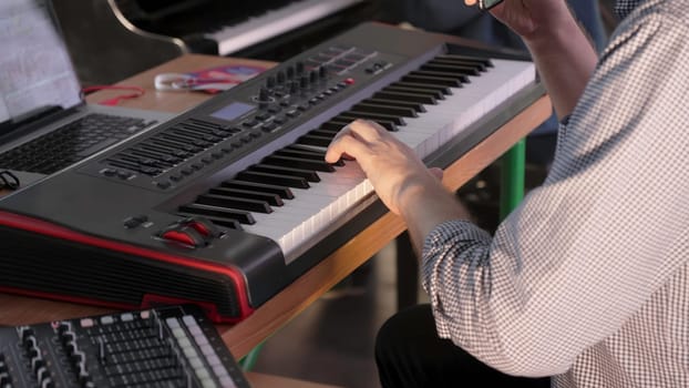 A talented musician passionately plays a keyboard, skillfully creating captivating music in a vibrant studio setting. Clip