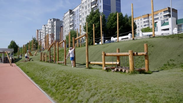 Georgia, Tbilisi - June 17, 2024: An urban park showcasing an array of play structures for children with modern residential buildings in the background. Clip