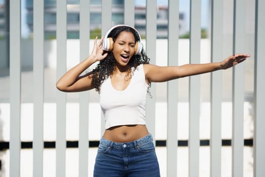 A vibrant and lively young woman dances joyfully to the rhythm of music, wearing her stylish headphones, showcasing her carefree spirit and profound love for music and dance in the open air