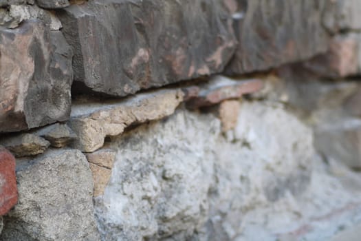 The wall features a variety of stones, showcasing different colors and textures, with visible signs of weathering under the warm afternoon light.