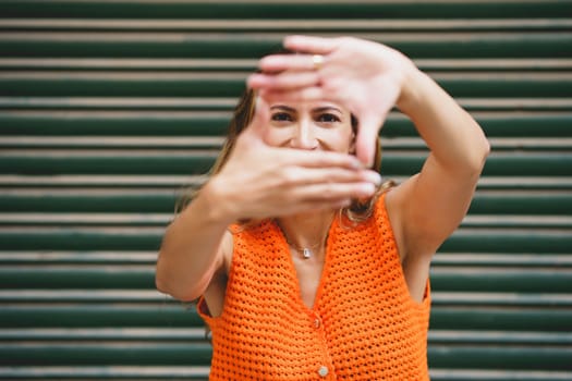 A latin woman framing with hands outdoors with urban background