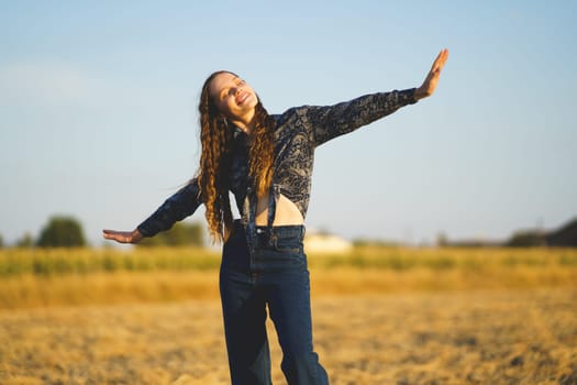 A joyful woman dances in a golden field, embodying freedom and happiness as she enjoys a vivid sunset, enhancing the moment with her energy and spirit, creating a warm, joyful scene