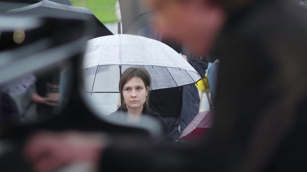 Georgia, Tbilisi - July 20, 2024: A thoughtful woman, sheltered by her umbrella, is listening intently to a talented pianists beautiful performance. Clip