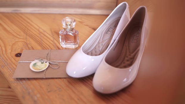 The video showcases a stylish wooden table featuring white shoes and an elegant perfume bottle, evoking modern fashion and beauty