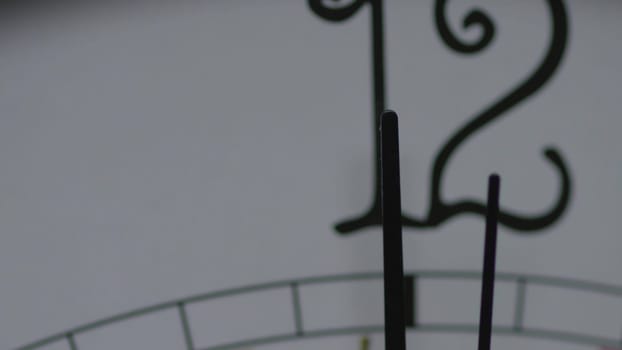 A detailed and closeup view of clock hands elegantly pointing towards twelve, beautifully capturing times essence