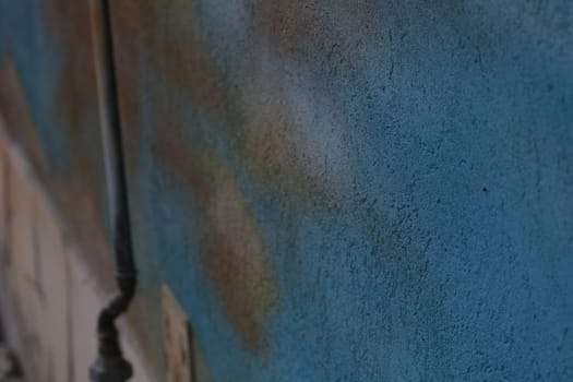 A textured blue wall features a colorful urban mural detail, highlighting the artistic expression found in a lively city. The scene reflects urban culture.