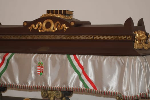 A beautifully crafted wooden coffin featuring intricate gold carvings is on display at a museum in Hungary, representing its rich cultural history and artistry.