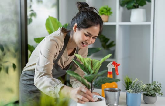 A young woman happily tends to her indoor garden, surrounded by vibrant plants and modern home decor.