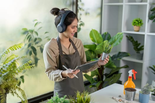A young woman enjoys gardening indoors, surrounded by vibrant plants and natural light, creating a peaceful and joyful atmosphere.