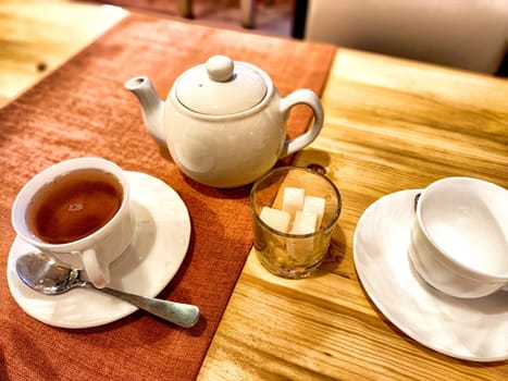 Enjoy a warm cup of tea served with sugar cubes and an elegant teapot, creating a relaxing afternoon ambiance.