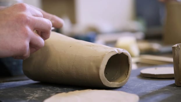 An artisan skillfully shapes the clay into a distinctive pottery piece within a vibrant creative workshop. Stock Clip