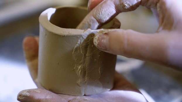 Hands skillfully repairing a delicate ceramic piece, showcasing the intricate artistry involved in pottery making. Stock Clip