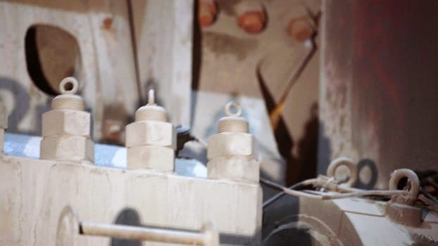 A thorough detailed view of various machinery parts, prominently showcasing bolts and connectors in a dusty setting. Stock Clip