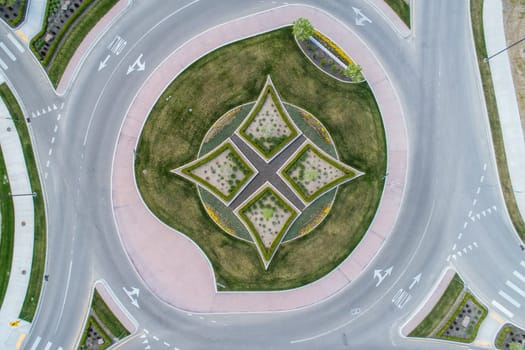 A round intersection with a grassy area in the middle. The grass is trimmed and the area is surrounded by a brick wall