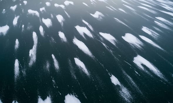 A body of water with a lot of snow on it. The snow is scattered all over the water, creating a beautiful and serene scene. Scene is peaceful and calm, as the snow covers the water