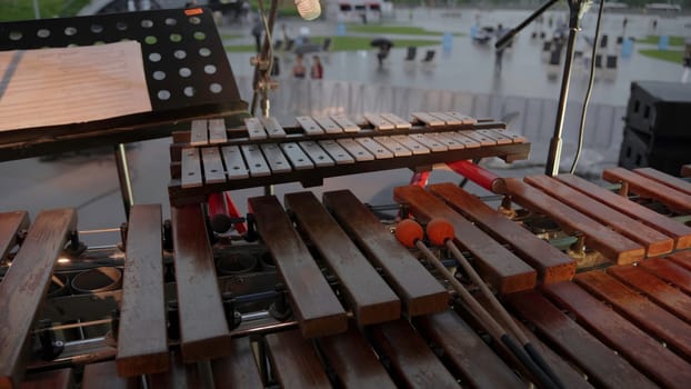 An artistic representation shows a xylophone setup designed for outdoor music performances in light rain. Clip