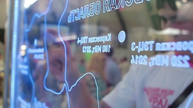 A man analyzes a map on a computer screen while another reviews a similar map on a glass wall, highlighting collaboration in navigation and exploration