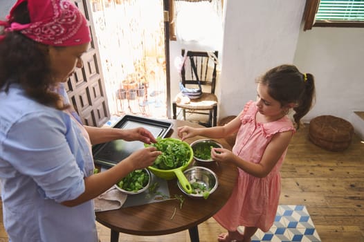A mother and daughter work together in a cozy kitchen, preparing a fresh green salad. The scene captures a warm, familial moment filled with joy, cooperation, and healthy living.