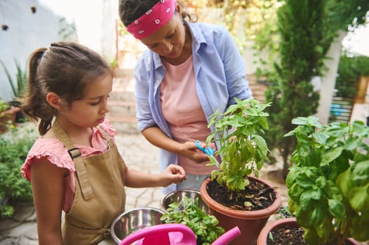 A mother and daughter enjoy a sunny day, gardening together in a backyard. They are tending to potted plants, sharing quality time while nurturing their green thumbs and enjoying nature.