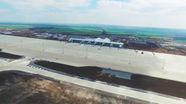 Experience the serenity of an airport runway from aerial views. Witness the contrast of tranquil tarmac and bustling planes, with a vibrant city skyline in the backdrop