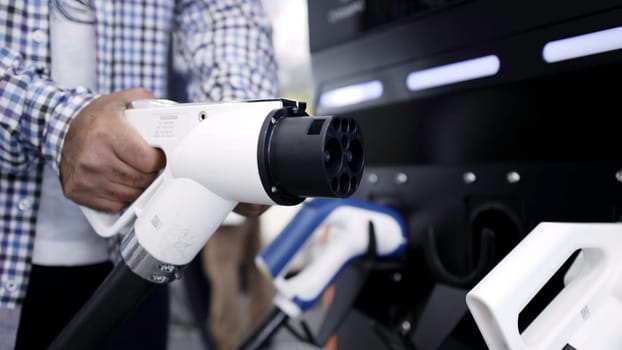 Close-up of fuel pump nozzles at a service station, showcasing electric and conventional fueling options. Media