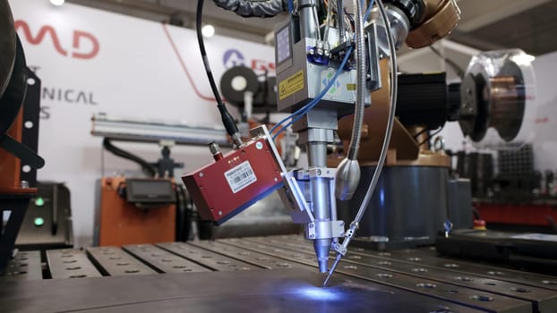 Dubai, UAE - June 2024: A robotic arm skillfully performs welding tasks using advanced lasers in a high tech manufacturing environment. Media