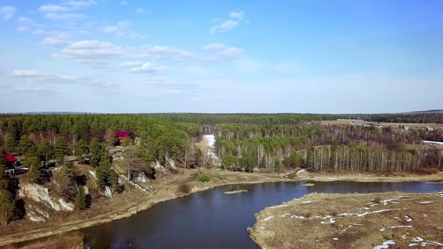 An impressive aerial view captures a lush green forest alongside a tranquil river set under a clear blue sky. Stock Clip
