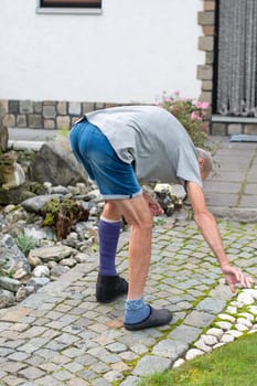 middle-aged man walks along a rocky path with a broken leg in a purple fibreglass cast, his foot shod in a special walking sandal,concept of an active lifestyle despite the limitations of an injury,
