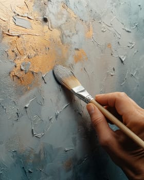 A hand applying paint with a brush to a surface. Selective focus.