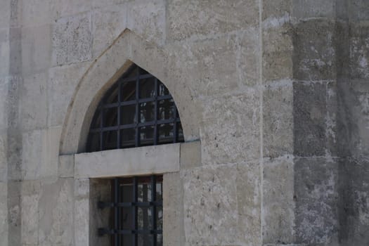 This architectural detail showcases a stone archway with a distinctive design, including a prominent metal grille. The structure reflects age and craftsmanship, typical of historic sites.