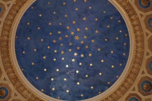 A beautifully decorated ceiling features an array of golden stars set against a deep blue background, creating a serene and enchanting atmosphere in the historic location.