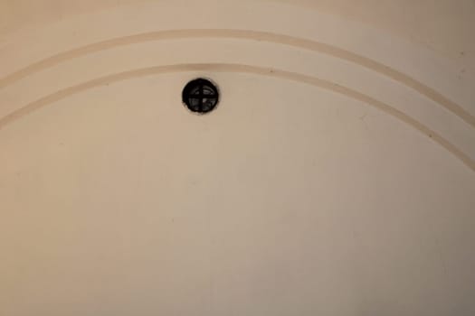 A circular ceiling vent is positioned centrally in a softly lit indoor area, enhancing the minimalistic decor while providing ventilation and comfort.