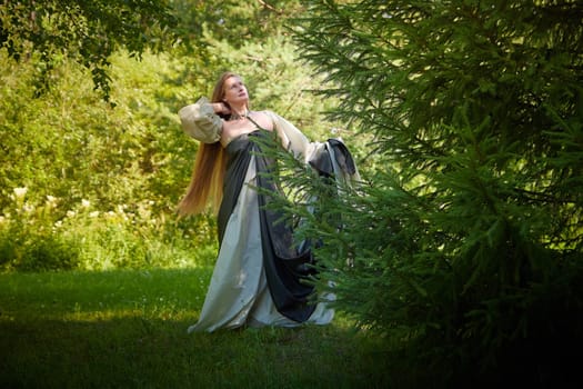 Beautiful dryad or fairy with gorgeous long hair in nature. Environmental friendliness, caring for nature. Adult mature woman 40-60 in Photo shoot
