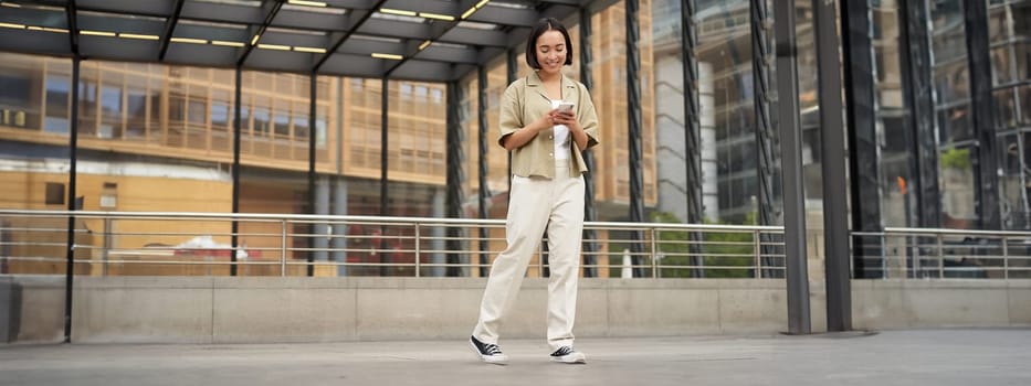 Portrait of asian female model with telephone. Young korean girl holding smartphone on street, using telephone.