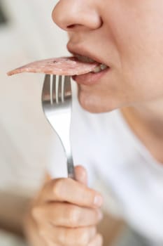 a woman stuffs sausage into her mouth. fast food and weight gain concept.