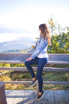 the girl sits on a bench on the mountain in Pilipets and looks at the fog.