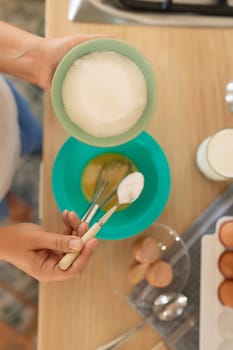 the cooking process, the woman adds ingredients to the pancake batter.